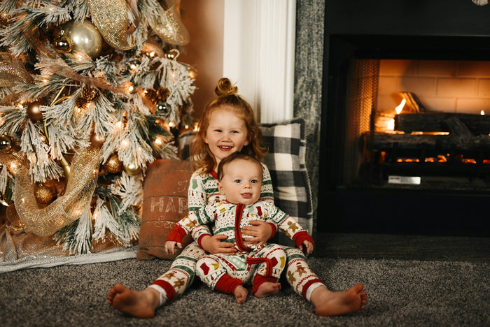Enfants en pyjama devant le sapin et la cheminée